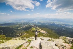 Picture of a man on the top of a hill embracing the world. An illustration in an article about finding the right marketing path.